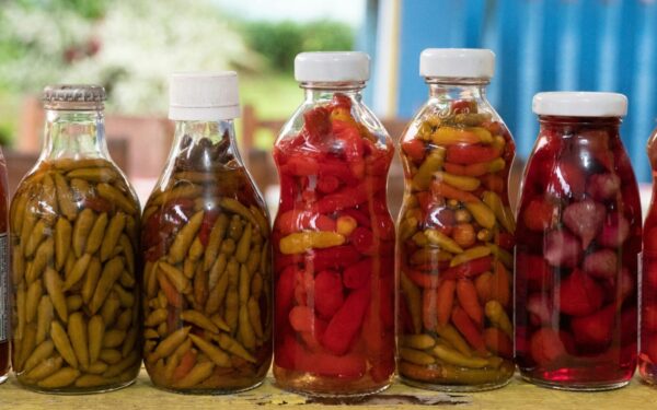 Close-up of vibrant pickled peppers in glass bottles captured in Morretes, Brazil.