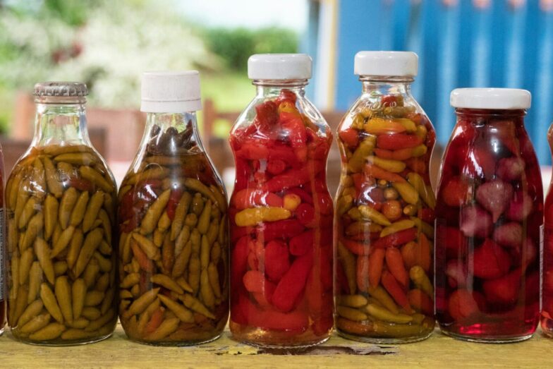 Close-up of vibrant pickled peppers in glass bottles captured in Morretes, Brazil.