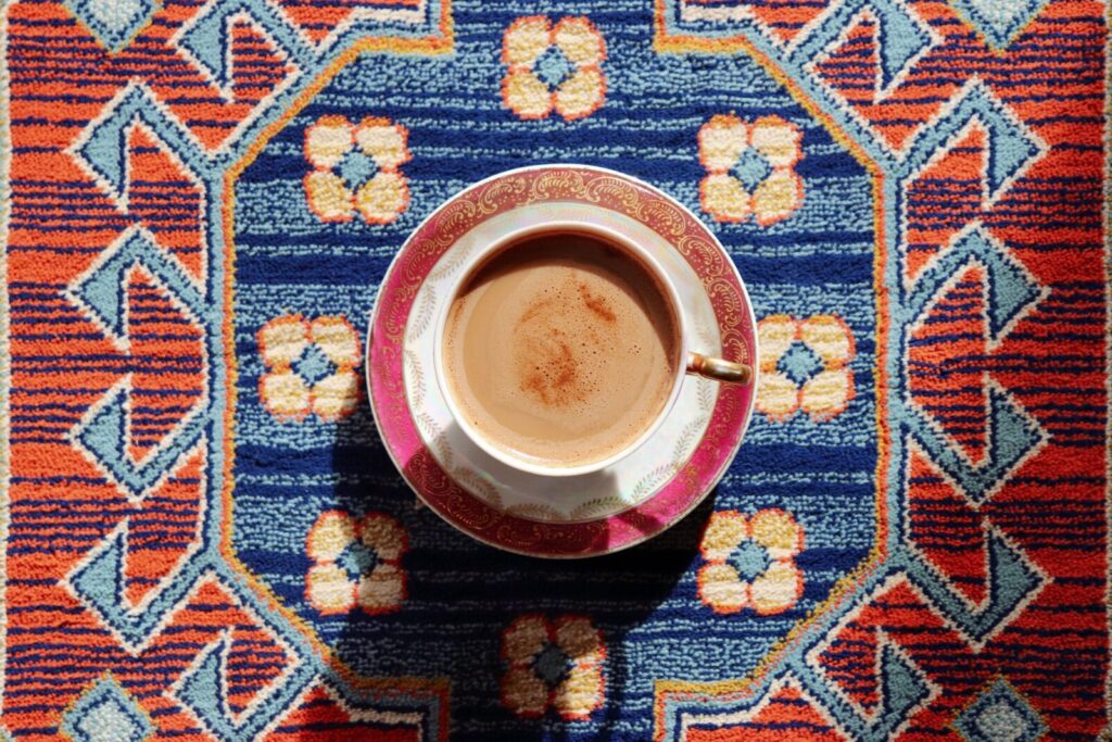 A top-down view of a coffee cup on a vibrant, geometric-patterned rug.