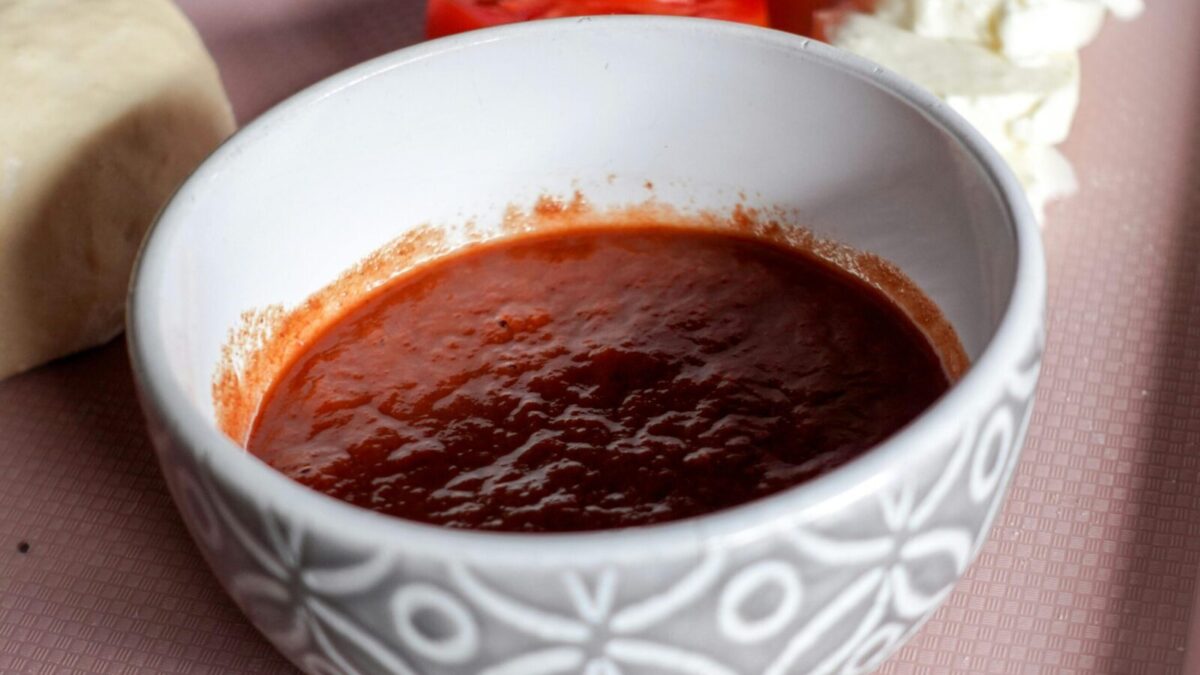 A bowl of tomato sauce surrounded by mozzarella cheese and sliced tomatoes, perfect for Italian cooking.