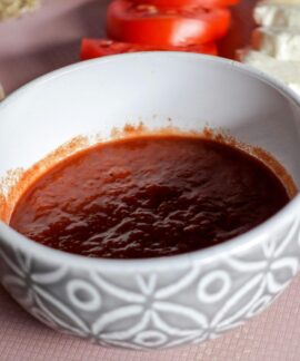 A bowl of tomato sauce surrounded by mozzarella cheese and sliced tomatoes, perfect for Italian cooking.