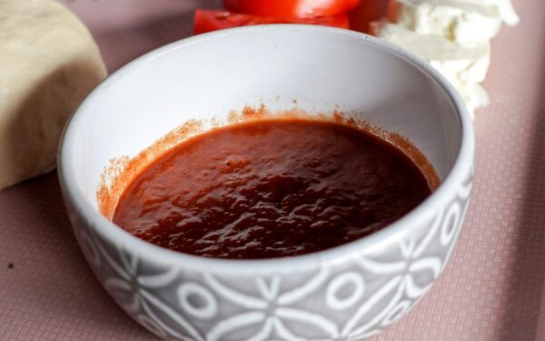 A bowl of tomato sauce surrounded by mozzarella cheese and sliced tomatoes, perfect for Italian cooking.