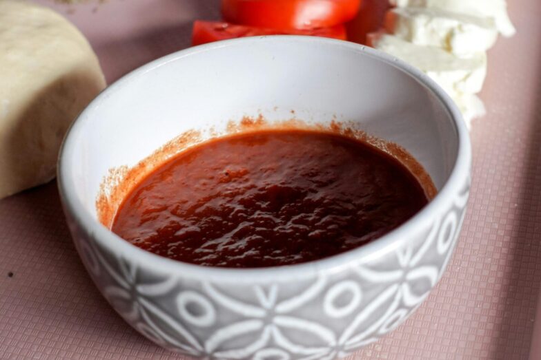 A bowl of tomato sauce surrounded by mozzarella cheese and sliced tomatoes, perfect for Italian cooking.
