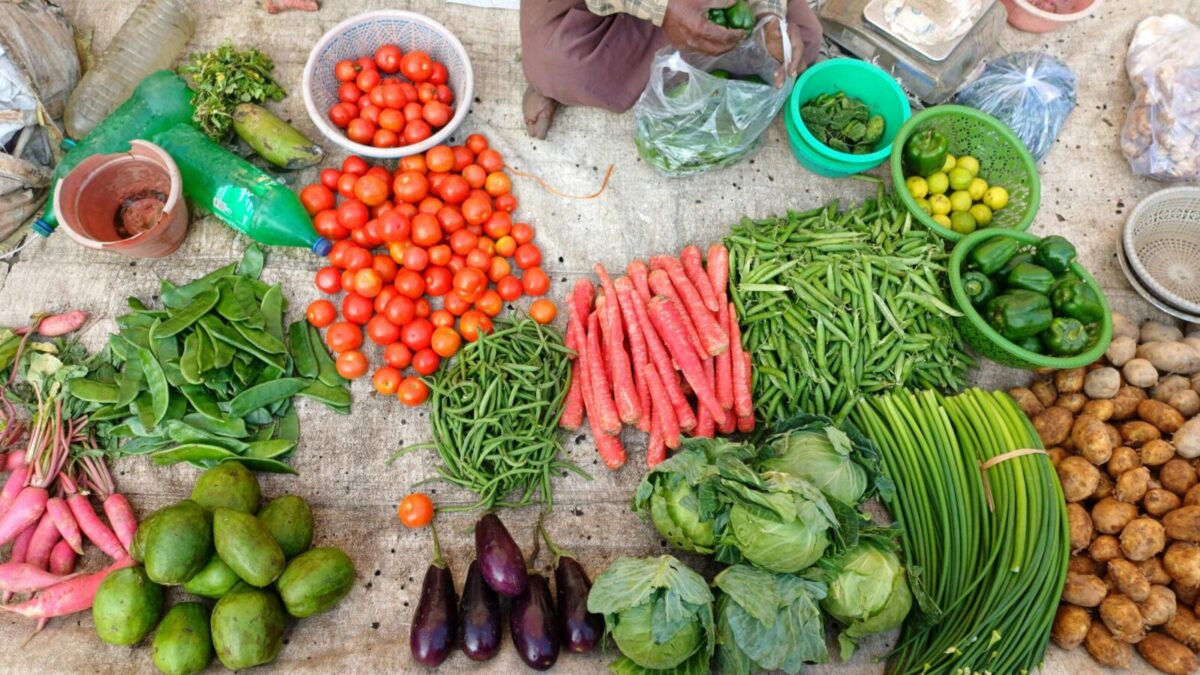 A vibrant display of fresh vegetables at an outdoor market stall.
