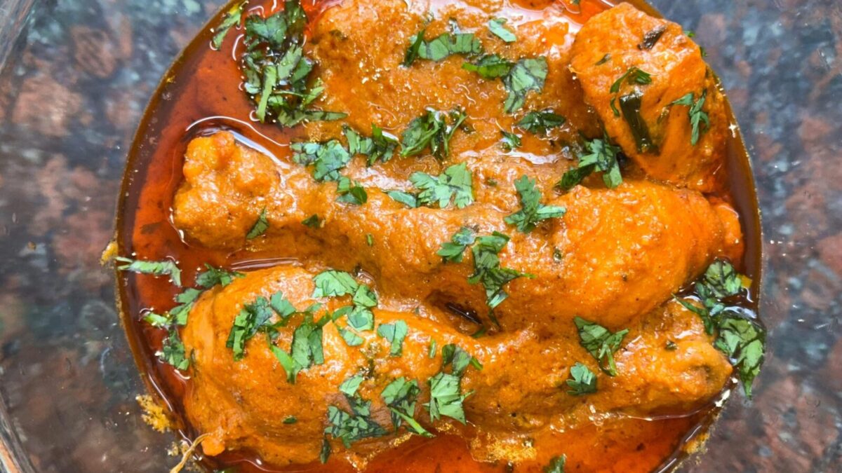 Close-up of a spicy chicken curry dish topped with fresh cilantro, perfect for Indian cuisine enthusiasts.