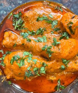 Close-up of a spicy chicken curry dish topped with fresh cilantro, perfect for Indian cuisine enthusiasts.