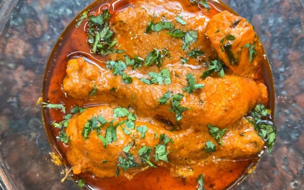 Close-up of a spicy chicken curry dish topped with fresh cilantro, perfect for Indian cuisine enthusiasts.