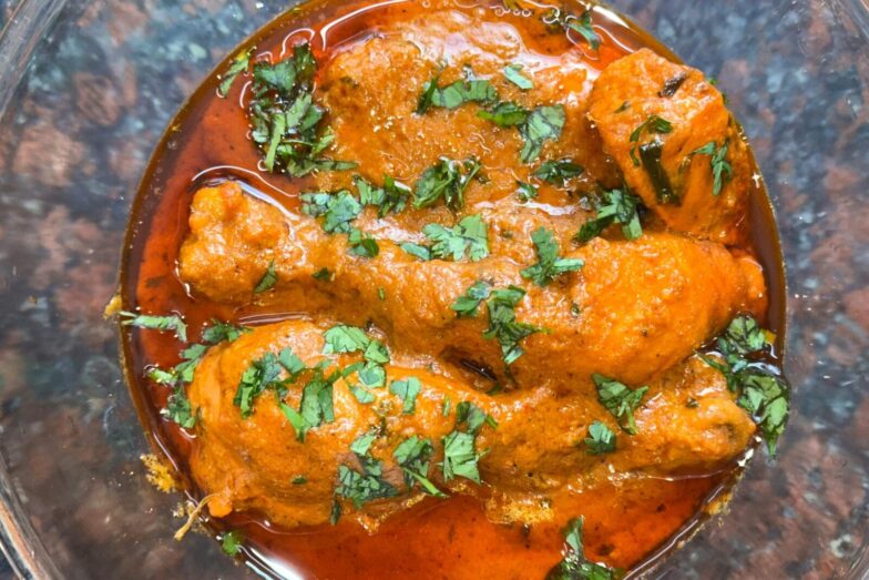 Close-up of a spicy chicken curry dish topped with fresh cilantro, perfect for Indian cuisine enthusiasts.