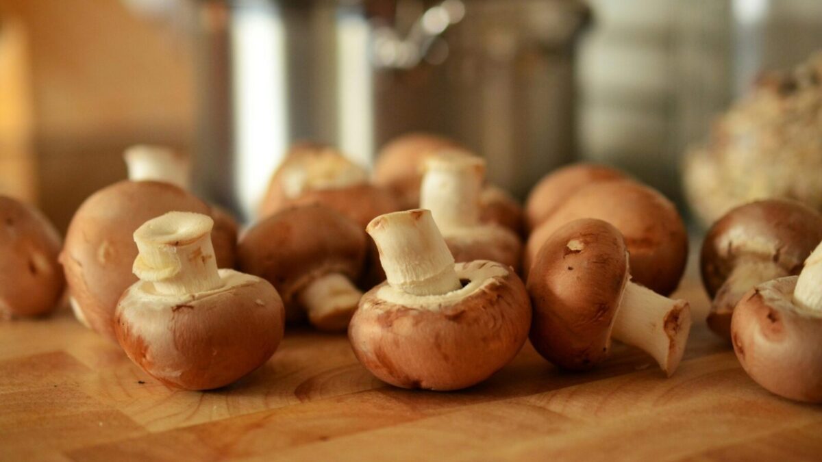 Close-up of fresh brown mushrooms on a wooden cutting board in a kitchen setting.