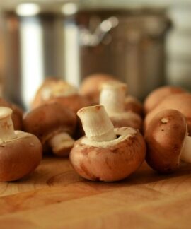 Close-up of fresh brown mushrooms on a wooden cutting board in a kitchen setting.
