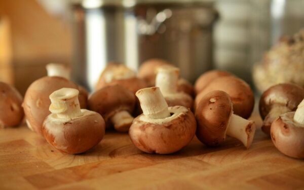Close-up of fresh brown mushrooms on a wooden cutting board in a kitchen setting.