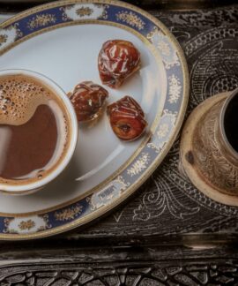 A close-up of traditional Turkish coffee with dates on an ornate serving tray for a cultural experience.