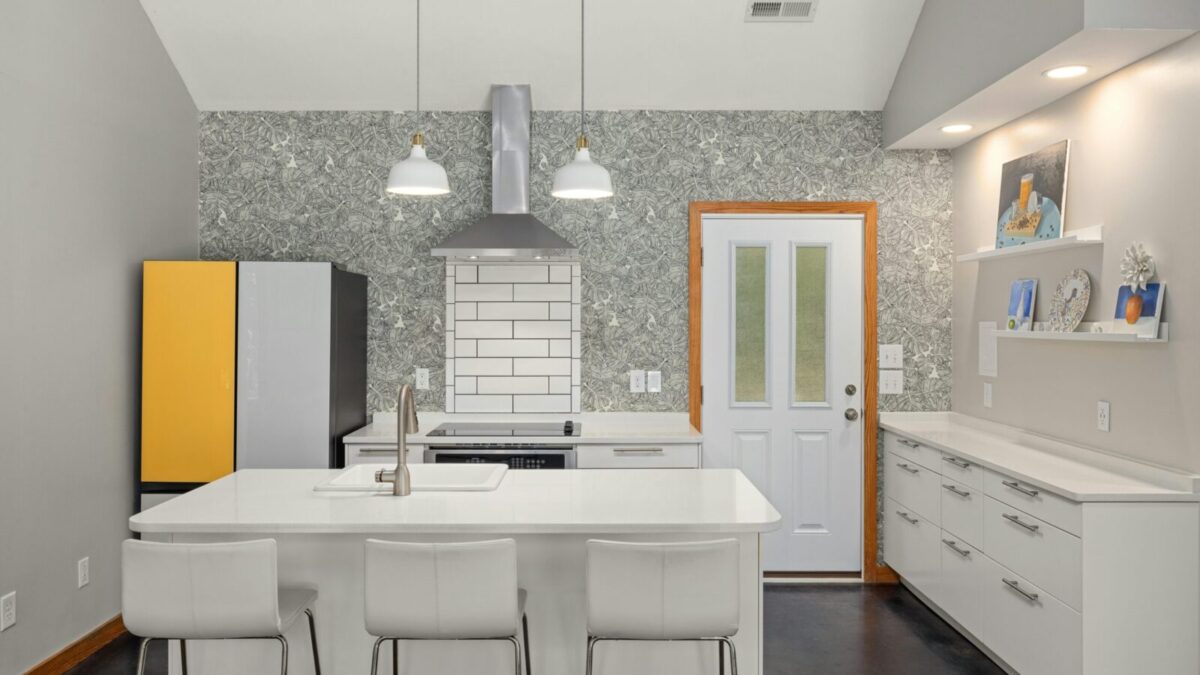 A sleek modern kitchen features a white island, vibrant fridge, and elegant lighting for a contemporary look.