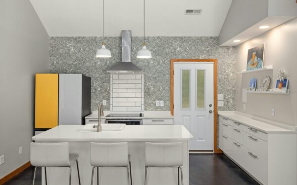 A sleek modern kitchen features a white island, vibrant fridge, and elegant lighting for a contemporary look.