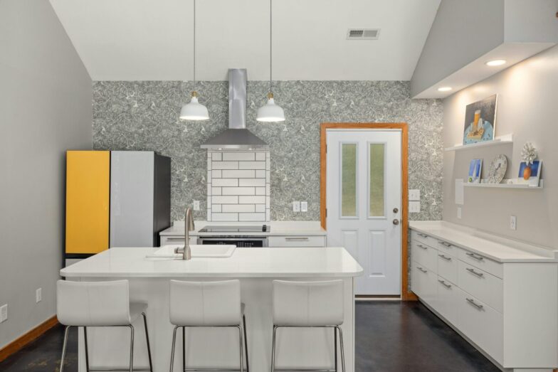 A sleek modern kitchen features a white island, vibrant fridge, and elegant lighting for a contemporary look.