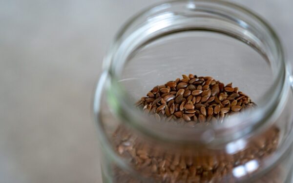 A clear glass jar filled with brown flax seeds, perfect for healthy cooking and baking.