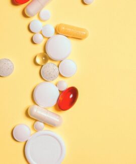 A collection of assorted pills and capsules on a vibrant yellow surface.