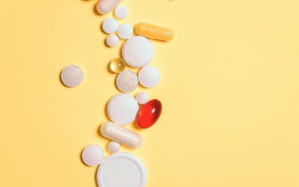 A collection of assorted pills and capsules on a vibrant yellow surface.
