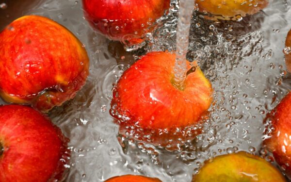 Vibrant red apples under a water stream, promoting cleanliness and freshness.