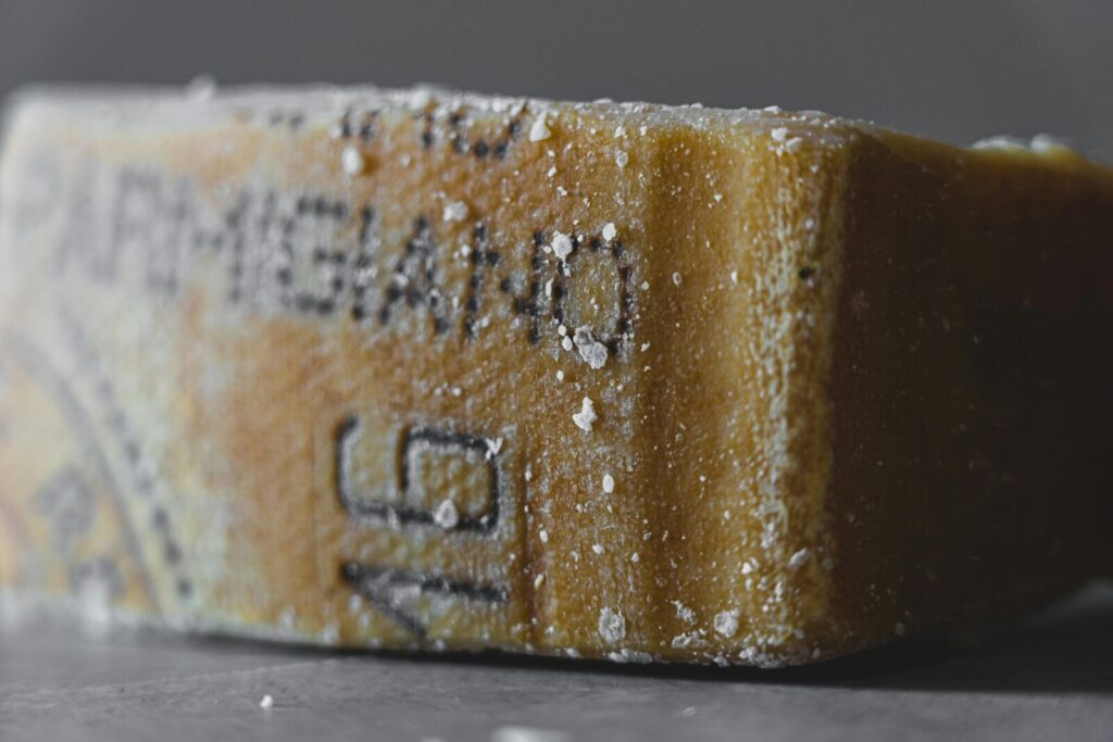 Detailed close-up of an aged Parmigiano cheese block, showcasing texture and salt crystals.