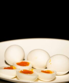 A white plate of hard-boiled eggs, some sliced, against a dark background.