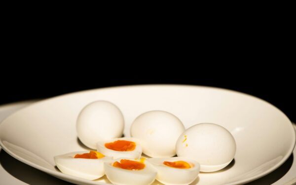 A white plate of hard-boiled eggs, some sliced, against a dark background.