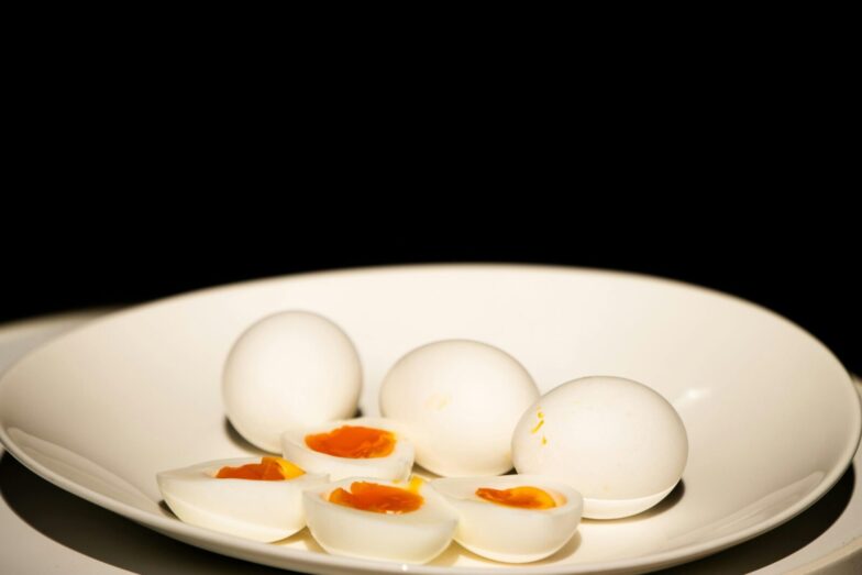 A white plate of hard-boiled eggs, some sliced, against a dark background.