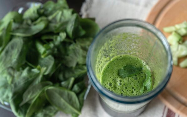 A refreshing green smoothie made with fresh spinach and cucumber on a wooden board.