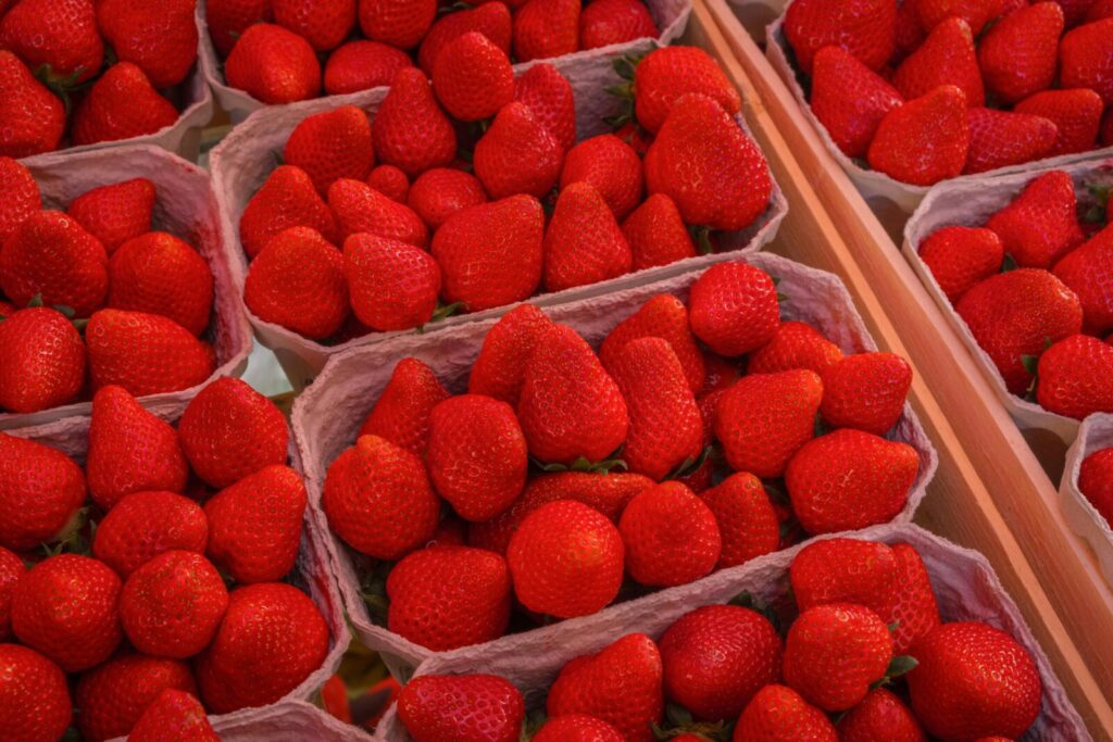 Vibrant red strawberries displayed in baskets at a market, ready to eat.