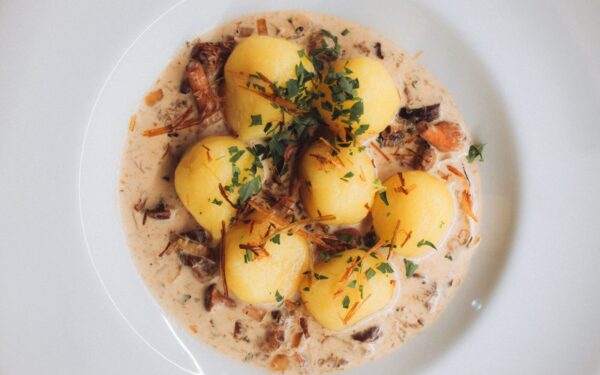 Close-up of traditional Polish dumplings served with a savory cream and mushroom sauce, garnished with fresh parsley.