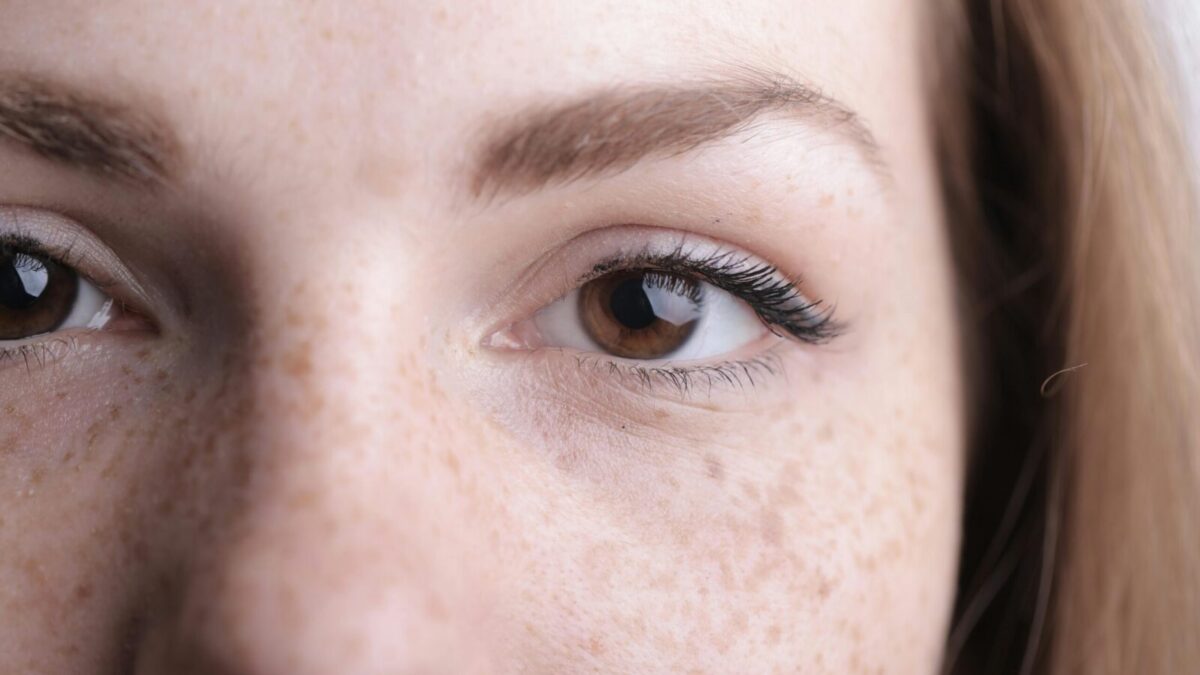 A detailed close-up of a woman's eye and freckles highlighting natural beauty.