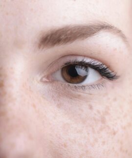 A detailed close-up of a woman's eye and freckles highlighting natural beauty.