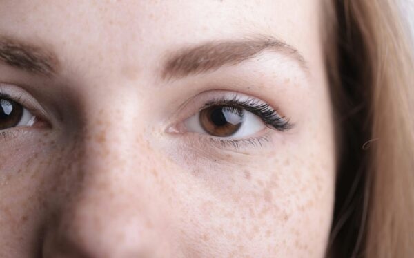 A detailed close-up of a woman's eye and freckles highlighting natural beauty.