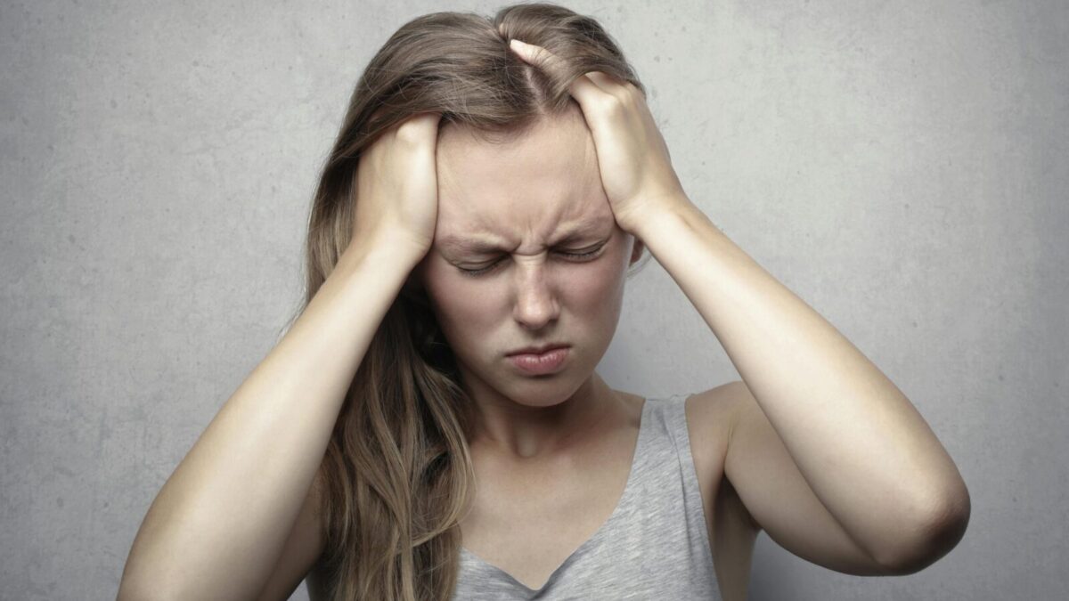 Young woman expressing stress and frustration while holding her head.