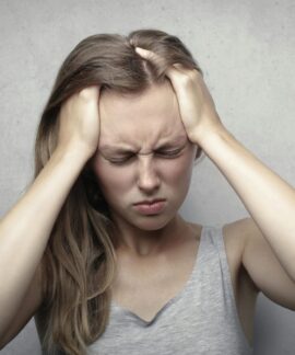Young woman expressing stress and frustration while holding her head.