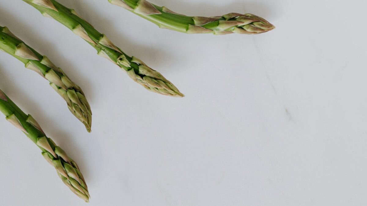 Close-up of fresh asparagus tips on a white background, highlighting freshness and healthy eating.