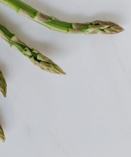 Close-up of fresh asparagus tips on a white background, highlighting freshness and healthy eating.