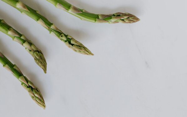 Close-up of fresh asparagus tips on a white background, highlighting freshness and healthy eating.
