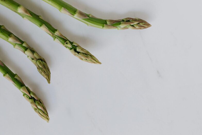 Close-up of fresh asparagus tips on a white background, highlighting freshness and healthy eating.