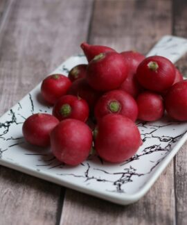 From above of fresh whole crunchy radishes on ornamental plate on wooden table at home