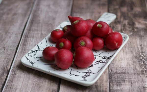 From above of fresh whole crunchy radishes on ornamental plate on wooden table at home