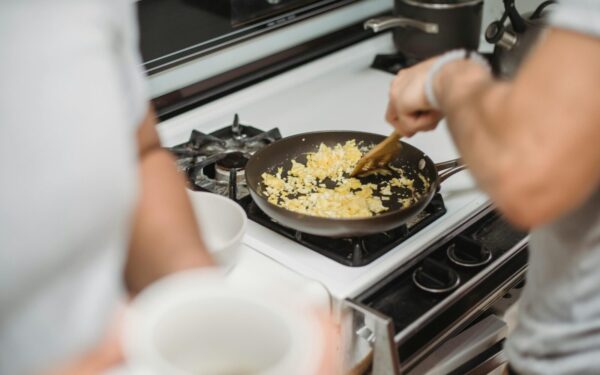 Close-up of a person cooking scrambled eggs on a stovetop, highlighting a cozy kitchen setting.