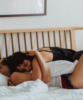 A loving couple embracing on a bed, showcasing warmth and intimacy in a cozy indoor setting.