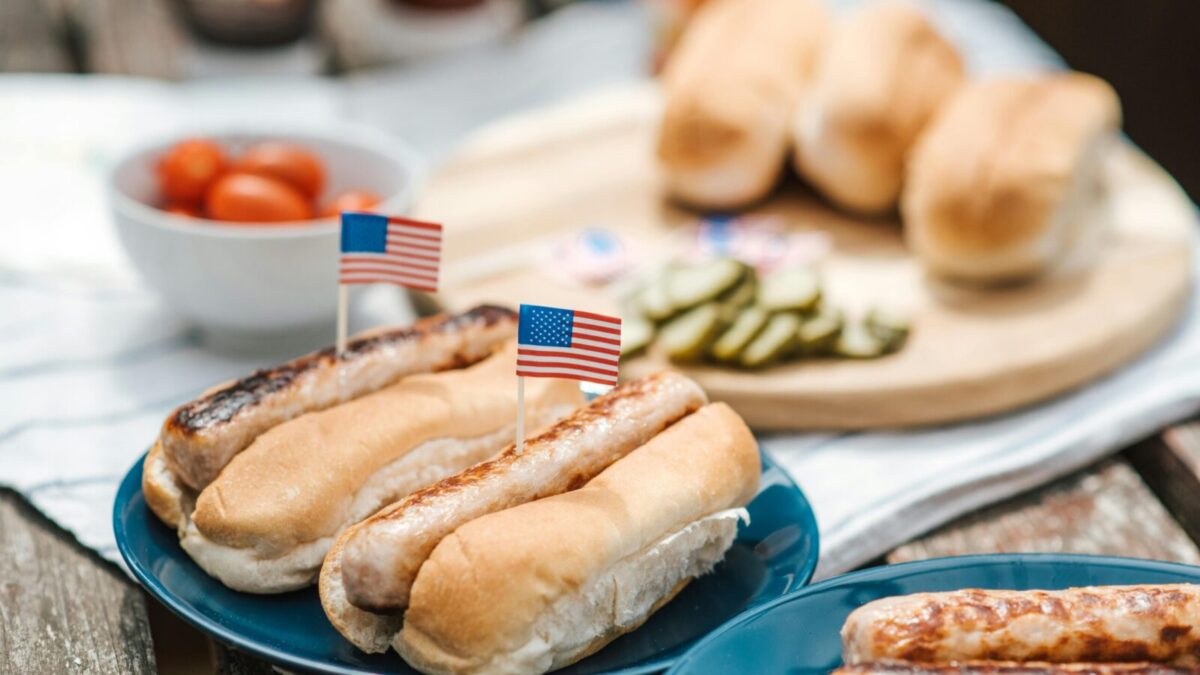 Hot dogs with American flags on a plate, perfect for a Fourth of July celebration.