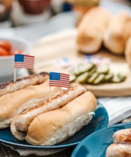 Hot dogs with American flags on a plate, perfect for a Fourth of July celebration.
