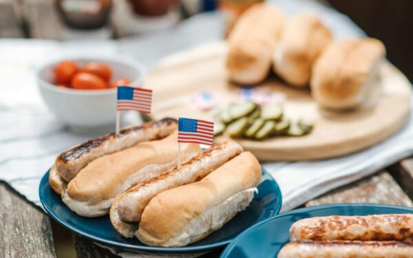 Hot dogs with American flags on a plate, perfect for a Fourth of July celebration.