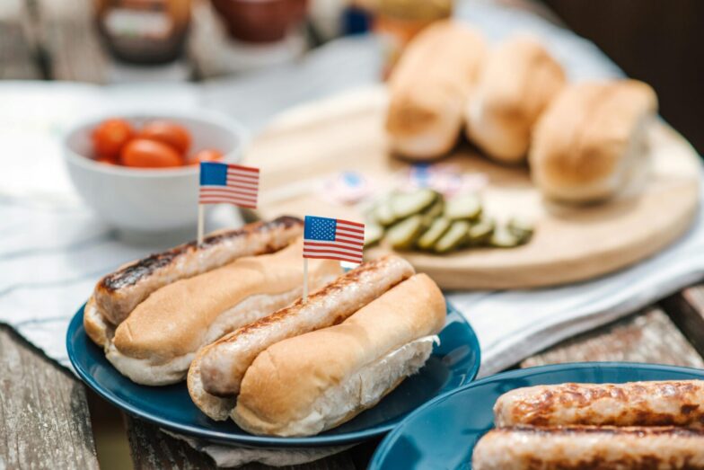 Hot dogs with American flags on a plate, perfect for a Fourth of July celebration.