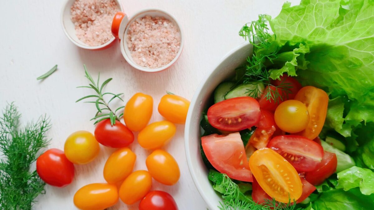 A vibrant assortment of fresh salad ingredients including tomatoes, lettuce, and Himalayan salt.
