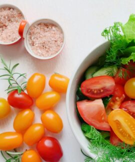 A vibrant assortment of fresh salad ingredients including tomatoes, lettuce, and Himalayan salt.