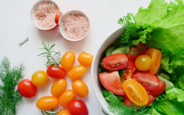 A vibrant assortment of fresh salad ingredients including tomatoes, lettuce, and Himalayan salt.